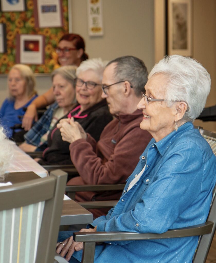 Senior residents sit together at the dining table, waiting to enjoy a meal.