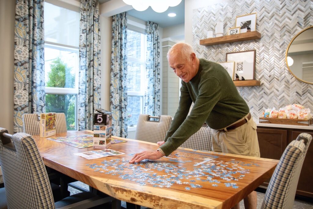 Residents doing a puzzle together on a gorgeous wooden table in one of the activity rooms.